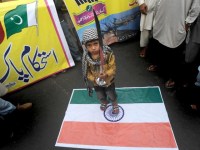 Pakistani boy standing on Indian flag