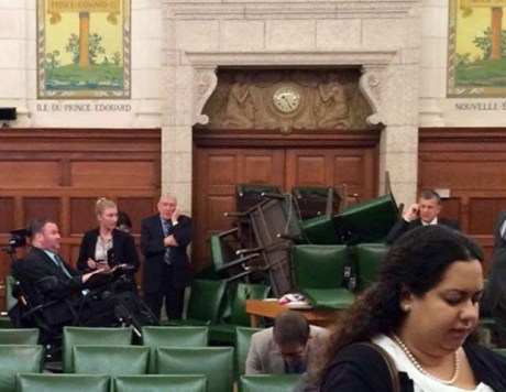 In this photo provided by Conservative MP Nina Grewal, members of Parliament barricade themselves in a meeting room on Parliament Hill in Ottawa, Canada, Wednesday, Oct. 22, 2014, after shots were fired in the building. A gunman with a scarf over his face shot to death a Canadian soldier standing guard at the nation's war memorial Wednesday, then stormed Parliament in a hail of gunfire before he was killed by the usually ceremonial sergeant-at-arms, authorities and witnesses said. (AP Photo/The Canadian Press, Nina Grewal)