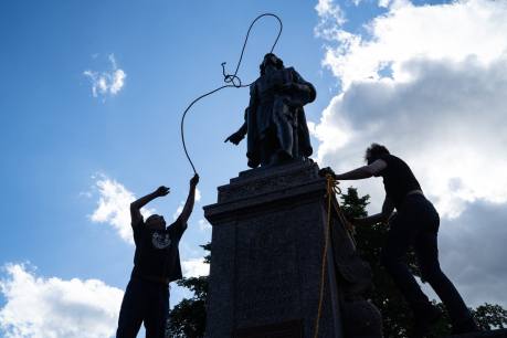 Mike Forcia, who is Anishanaabe, left, and another man fasten ropes around the neck of a statue of Christopher Columbus at the Minnesota State Capitol in St. Paul on June 10, 2020.