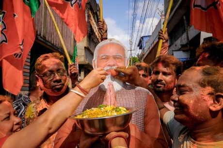 BJP workers in Howrah offer sweets to a cutout of PM Modi.